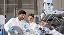 Superconductors transmit electric power with negligible line losses and have high current-carrying capacity compared to copper. This will make it possible to generate and transmit electricity in a resource-saving manner in future.
For the efficient production of high-temperature superconductors Deutsche Nanoschicht GmbH, a BASF Group company, has developed a unique process: very thin films of a superconducting material are applied to a metal strip in a continuous process by a technique called chemical solution deposition. In contrast to other, physical methods, the chemical process requires neither a vacuum nor a clean room environment. This provides a decisive advantage for the production costs of the superconducting wires.
Anushka Kudaliyange (left) and Margot Ledwon-Brzezina (right), both employees of Analytics and Pilot Production, examine metal substrates before coating. Superconductors transmit electric power with negligible line losses and have high current-carrying capacity compared to copper. This will make it possible to generate and transmit electricity in a resource-saving manner in future.
For the efficient production of high-temperature superconductors Deutsche Nanoschicht GmbH, a BASF Group company, has developed a unique process: very thin films of a superconducting material are applied to a metal strip in a continuous process by a technique called chemical solution deposition. In contrast to other, physical methods, the chemical process requires neither a vacuum nor a clean room environment. This provides a decisive advantage for the production costs of the superconducting wires.
Anushka Kudaliyange (left) and Margot Ledwon-Brzezina (right), both employees of Analytics and Pilot Production, examine metal substrates before coating.