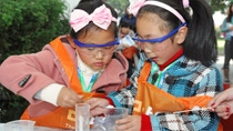 Two little girl wearing pink head bands and safety goggles working on a science experiment  Two little girl wearing pink head bands and safety goggles working on a science experiment
