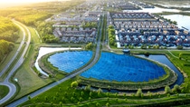 Foto aérea de una ciudad. Tiene avenidas en el lado izquierdo, un lago en el centro rodeado de zona verde y un conjunto de casas detrás.