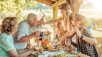 Cheerful women and men sitting around a table full of food and celebrating.