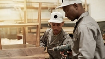 Cropped shot of two young male carpenters putting together a wood piece in their workshop Cropped shot of two young male carpenters putting together a wood piece in their workshop