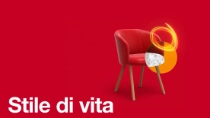A red armchair with wooden legs in front of a red background, with a glowing light-ring effect. The text reads: "Lifestyle."