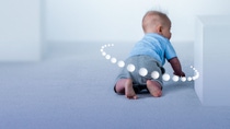 Cute baby with graphic circles around crawling towards white block  Cute baby with graphic circles around crawling towards white block