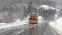 Tractor driving on a road surrounded by snow