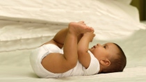 A happy baby wearing a diaper is lying on its back.