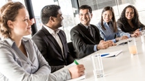 A diverse group of employees participates in a meeting, exchanging ideas and engaging in discussion around a conference table. 