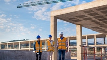 Three people standing in front of a construction site. Three people standing in front of a construction site.