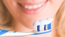 Smiling woman holding a glue tooth brush with toothpaste