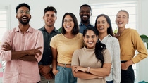 A group of young talents stand in a bright office room and smile at the camera. A group of young talents stand in a bright office room and smile at the camera.