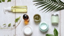 overhead view of assortment of creams and liquids on table amidst greenery overhead view of assortment of creams and liquids on table amidst greenery