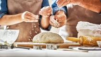 Close up view of bakers are working. Homemade bread. Hands preparing dough on wooden table. 
