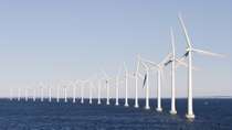 Una fila di turbine eoliche bianche nell’oceano sotto un cielo limpido