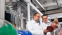 Two scientist wear red safety goggles analyzing chemical holding cue cards  Two scientist wear red safety goggles analyzing chemical holding cue cards