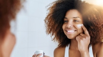 A young woman applying cream on her face. A young woman applying cream on her face.