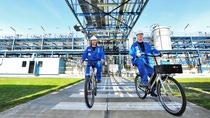 Twee medewerkers fietsen over het buitenterrein bij BASF Heerenveen