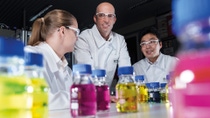 Three people examine color samples of various radiator protection agents. Three people examine color samples of various radiator protection agents.