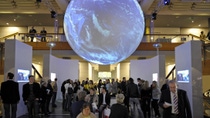 exhibit space with projected earth hanging above crowd  exhibit space with projected earth hanging above crowd