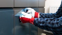 Home Improvement, handyman removing protective film on newly installed kitchen counter doors.