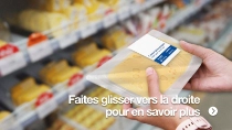 Une personne tient une barquette plastique de fromage en tranches dans une épicerie. Le fond comporte des étagères où sont présentés différents types de fromages. Une personne tient une barquette plastique de fromage en tranches dans une épicerie. Le fond comporte des étagères où sont présentés différents types de fromages.