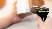 Person holding a black price scanner while scanning an item Person holding a black price scanner while scanning an item