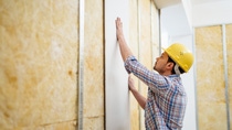 Construction worker on construction site building up a drywall.