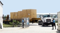 A man opens a gate through which a truck is driving A man opens a gate through which a truck is driving