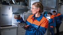 Mit B2Last hat BASF ein innovatives Bitumenadditiv entwickelt, das die Asphaltperformance mit der Nachhaltigkeit vereint: Temperaturabgesenkter Einbau bei gleichzeitig hohem Asphaltgranulatanteil wird durch den Einsatz von B2Last bei konstant guter Verarbeitbarkeit möglich. So entstehen deutlich geringere Bitumen- und CO2-Emissionen als bei herkömmlichen Anwendungen. Zusätzlich wird die Widerstandsfähigkeit des Asphaltes verbessert. Dadurch verlängert sich die Lebensdauer der Straße. Anne Holzum, Chemielaborantin, kontrolliert, inwieweit sich die Marshall-Probekörper durch Belastung in einem Druckschwellversuch verformt haben. In der rechten Hand hält Anne Holzum einen Probekörper mit dem Bitumenadditiv B2last. In der linken Hand hält sie einen Probekörper ohne B2Last.