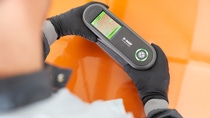 Two hands holding a spectrophotometer on an orange car