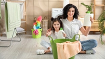 Mother and daughter are sitting in the bathroom, around them are cleaning products.