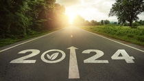 New year 2024 straightforward for environmental sustainability concept. Text 2024, save the world, environment protection icon on the road in the middle of asphalt road at sunset. Ecological balance.