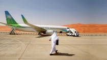 A person walks across a runway to the plane in Saudi Arabia. A person walks across a runway to the plane in Saudi Arabia.
