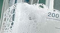 Close up of a glass beaker with foam bubbles