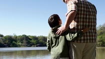 Man and boy standing at a lake  Man and boy standing at a lake