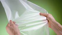 Hands pulling apart florescent plastic sheet 
