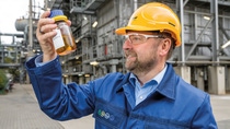 Een BASF-collega met een fles pyrolyse-olie teruggewonnen uit plastic afval Een BASF-collega met een fles pyrolyse-olie teruggewonnen uit plastic afval