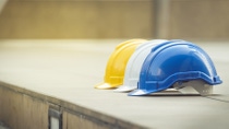 white, yellow and blue hard safety helmet hat for safety project of workman as engineer or worker, on concrete floor on city white, yellow and blue hard safety helmet hat for safety project of workman as engineer or worker, on concrete floor on city