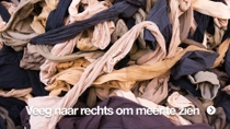Close-up van een grote stapel afvalkledingstukken in verschillende kleuren, in elkaar verstrikt.  Close-up van een grote stapel afvalkledingstukken in verschillende kleuren, in elkaar verstrikt.