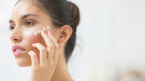 Woman applying moisturizer to cheek Woman applying moisturizer to cheek