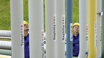 Dwóch pracowników w niebieskich kombinezonach sprawdza duże rury w różnych kolorach, które transportują podstawowe składniki, takie jak nafta, do produkcji chemicznej. Dwóch pracowników w niebieskich kombinezonach sprawdza duże rury w różnych kolorach, które transportują podstawowe składniki, takie jak nafta, do produkcji chemicznej.