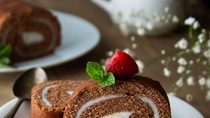 Delicious chocolate roll sponge cake with vanilla cream and mint leaves, Desert sweet food Delicious chocolate roll sponge cake with vanilla cream and mint leaves, Desert sweet food