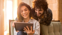 Young smiling couple reading something on digital tablet at home.