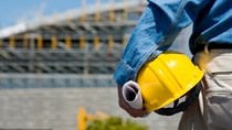 A construction worker or foreman at a construction site observing the progress of construction job or project, with copy space
