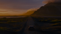 A car in a mountainous landscape driving into the sunset. A car in a mountainous landscape driving into the sunset.