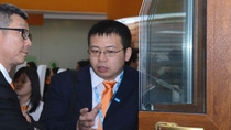 Two men in suits and orange tie at a conference