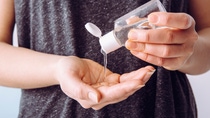 Close up view of woman person using small portable antibacterial hand sanitizer on hands.