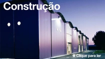 Um exterior moderno do edifício ao anoitecer com luzes acesas.&nbsp; O texto na imagem diz: “Construção”