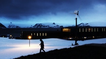 A man walking through a snowy landscape with houses in the background at night