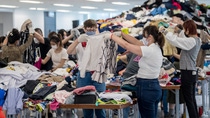 A group of people sorting through piles of clothing.
