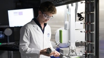 SOLVE scientist wearing white coat and safety glasses in research lab