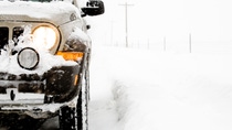 SUV 4x4 on a snowy day, illuminated headlight, close up with limited dof and copyspace